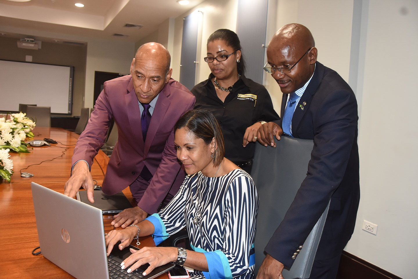 Allan Lewis (from left) managing director and Sharon Whitelocke, deputy general manager, JN Fund Managers, give a demonstration to Leesa Kow (seated), deputy managing director, JN Bank and Michael Powell, senior manager, security department, JN Group. They were viewing the new online platform launched by JN Fund Managers.