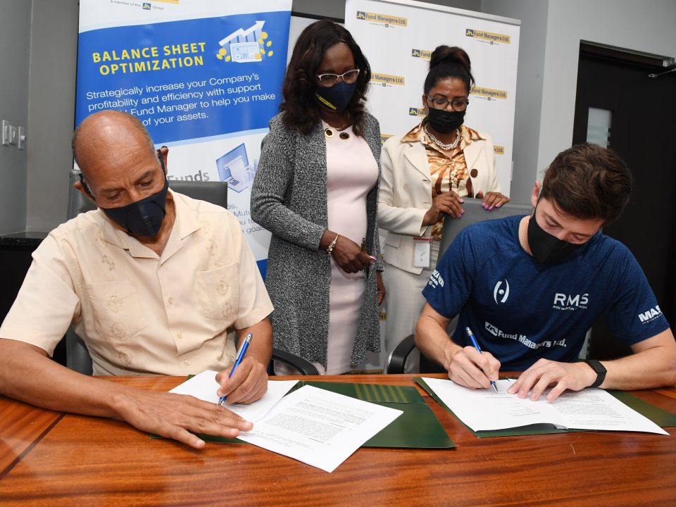 Allan Lewis (left), Managing Director of JN Fund Managers and Christopher Binnie, Jamaica’s top squash player sign partnership agreement. Sharing in the moment are Delories Jones (standing at left), Senior Vice President of Sales Strategy and Marketing, JN Fund Managers and Sharon Whitelocke, Deputy General Manager, JN Fund Managers.